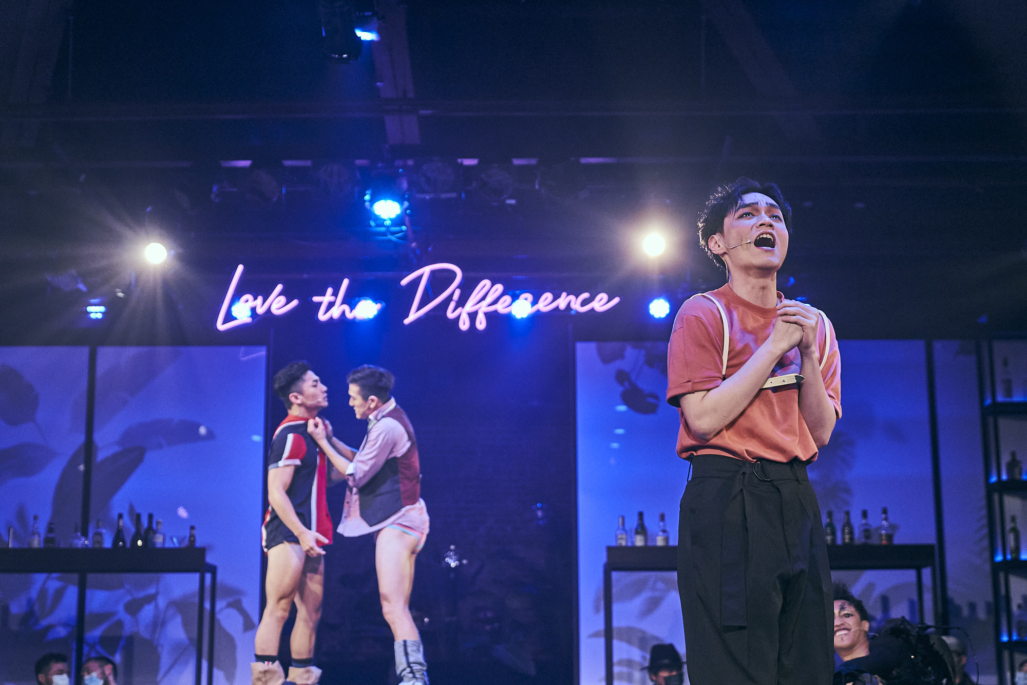 Solo performer under Love the Difference neon sign