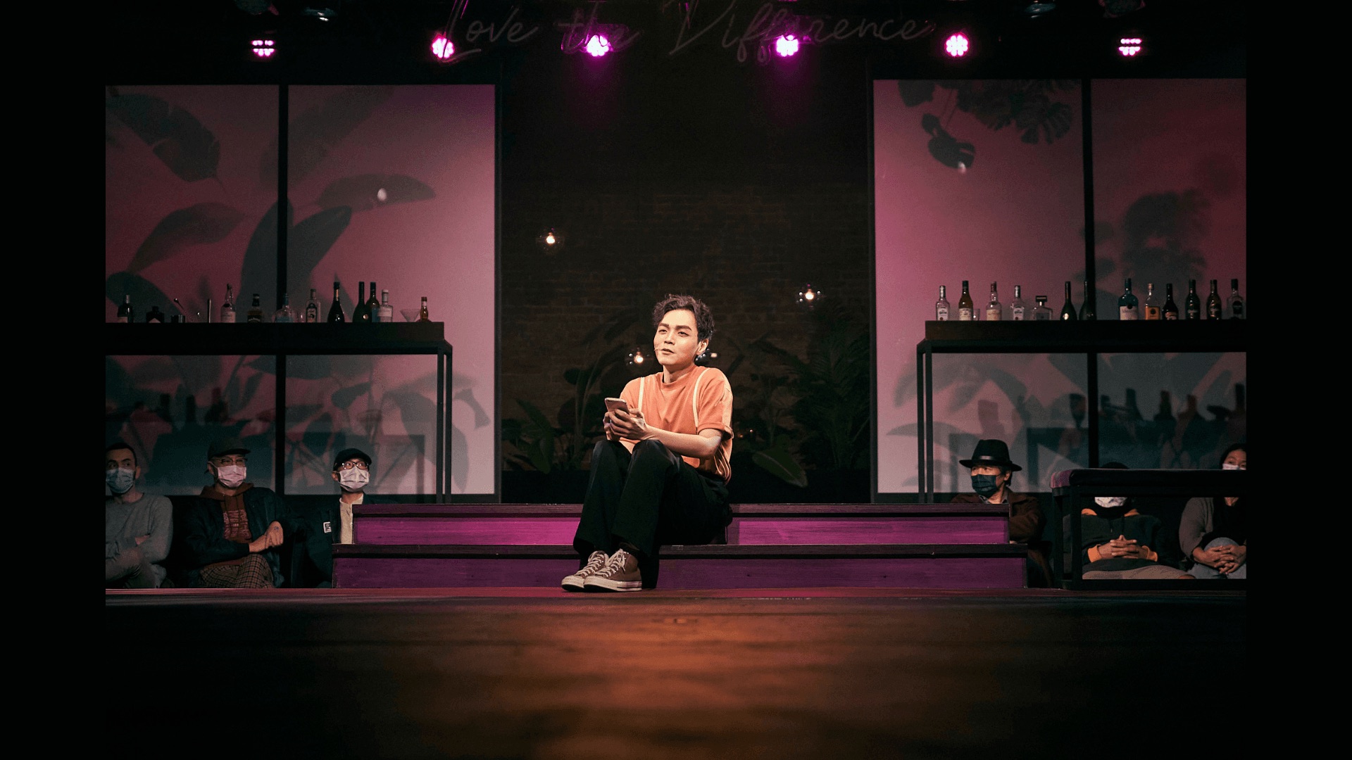 Solo performer in pink light with audience