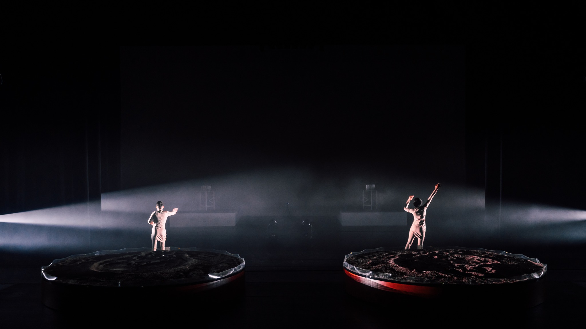 Two performers on platforms with haze