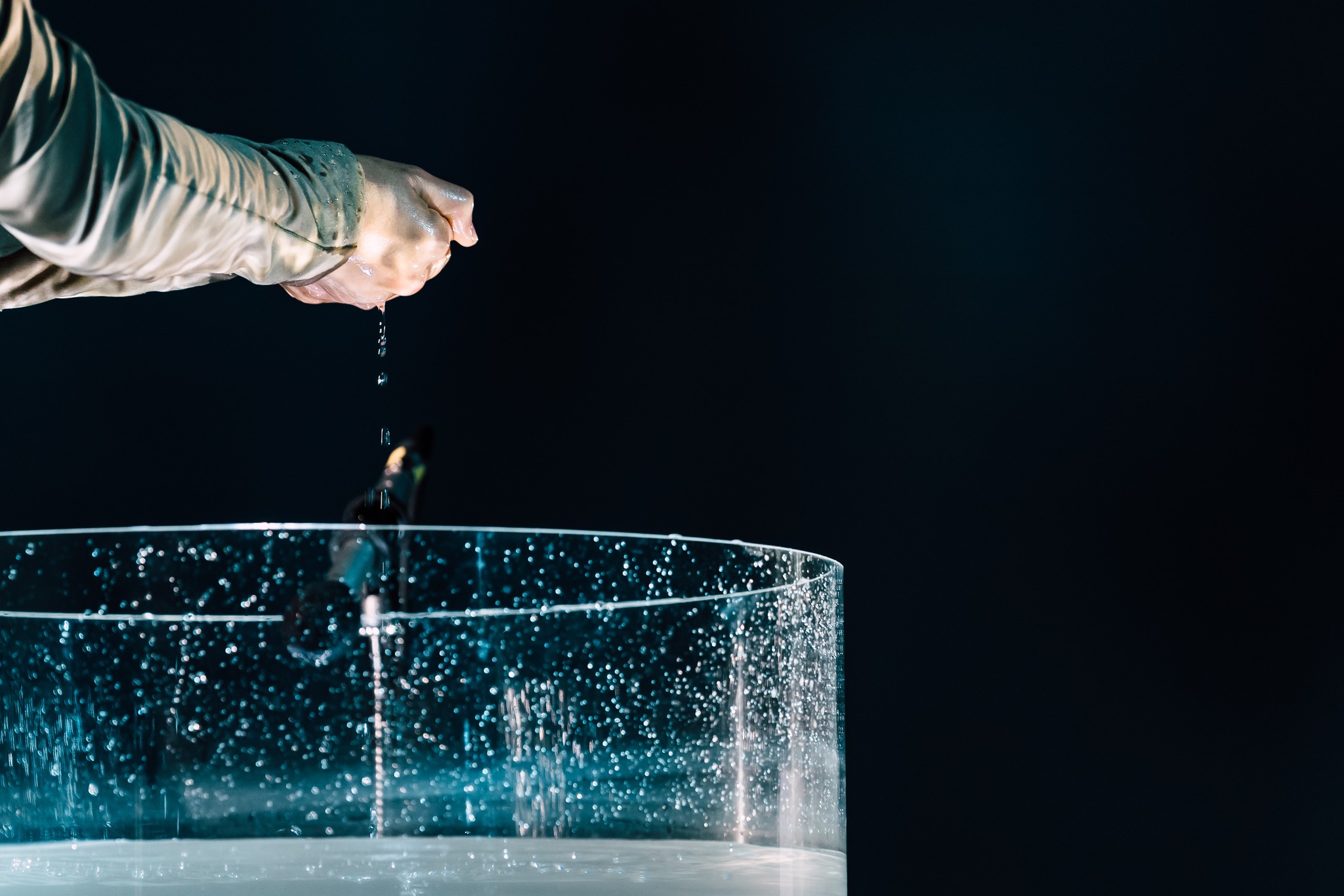 Hand squeezing water over glass vessel
