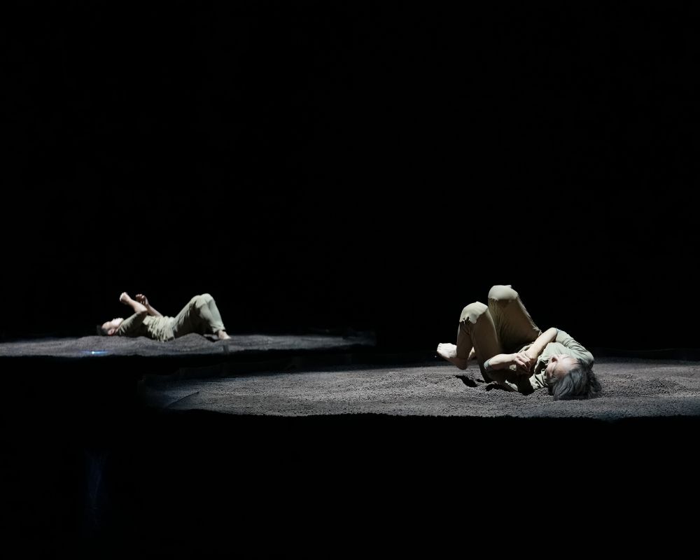 Performers lying on soil platforms
