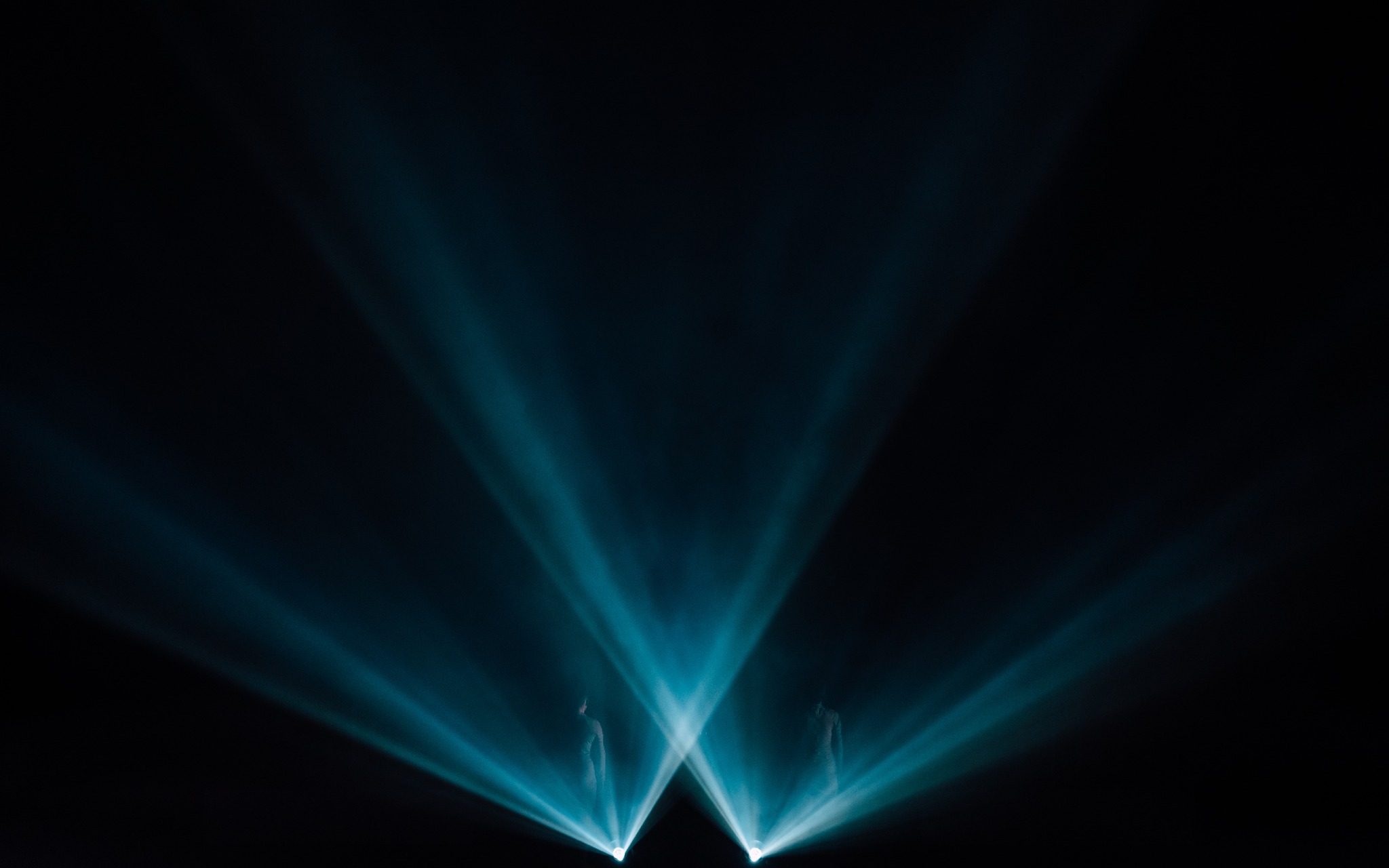 Two performers in teal light beams