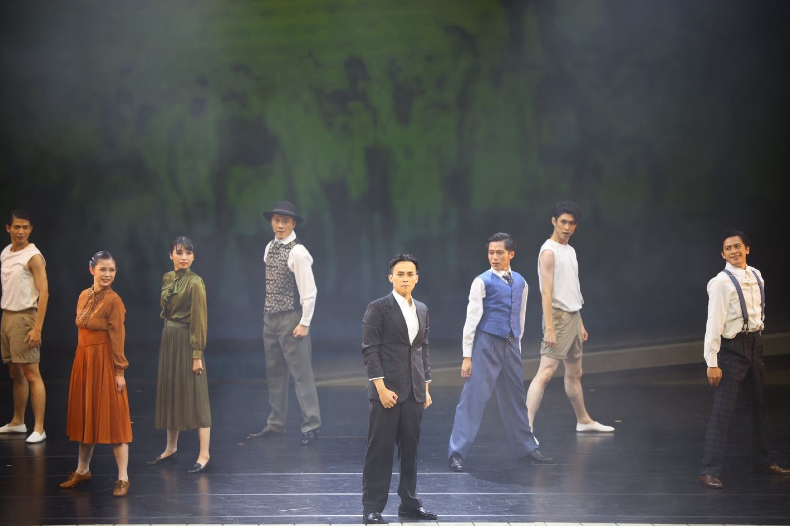 Ensemble in period costumes with lead in black suit