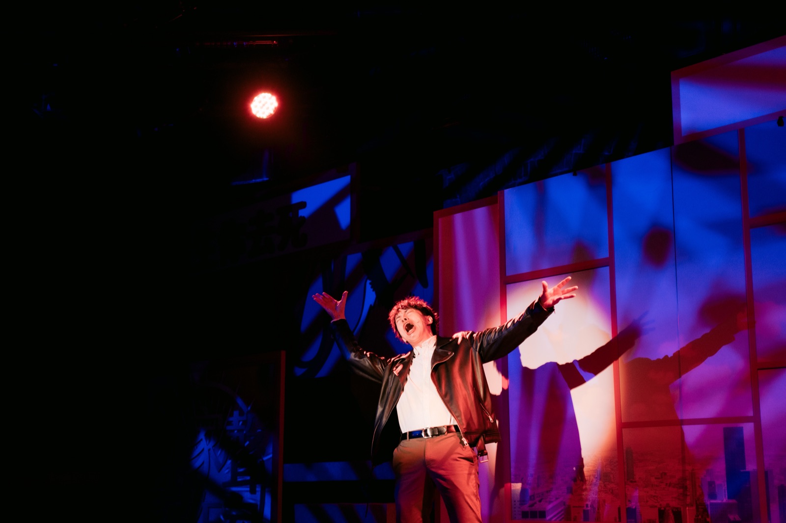 Man singing with arms wide in purple window light
