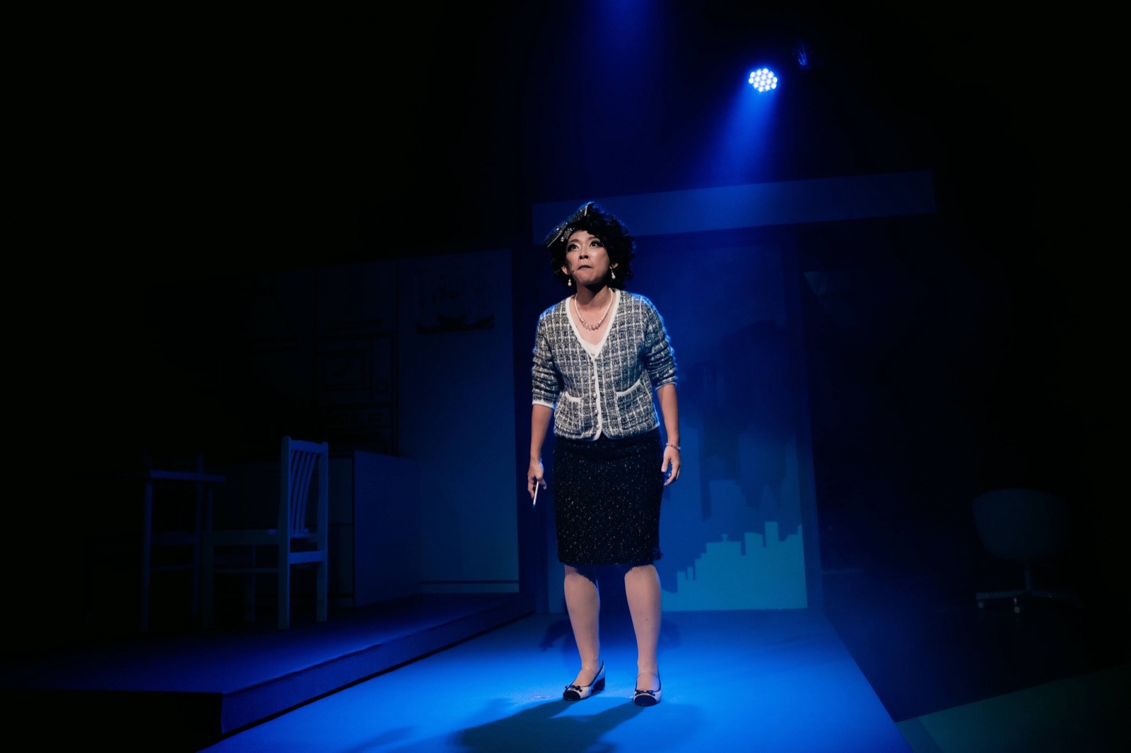 Solo performer in blue spotlight with cityscape projection