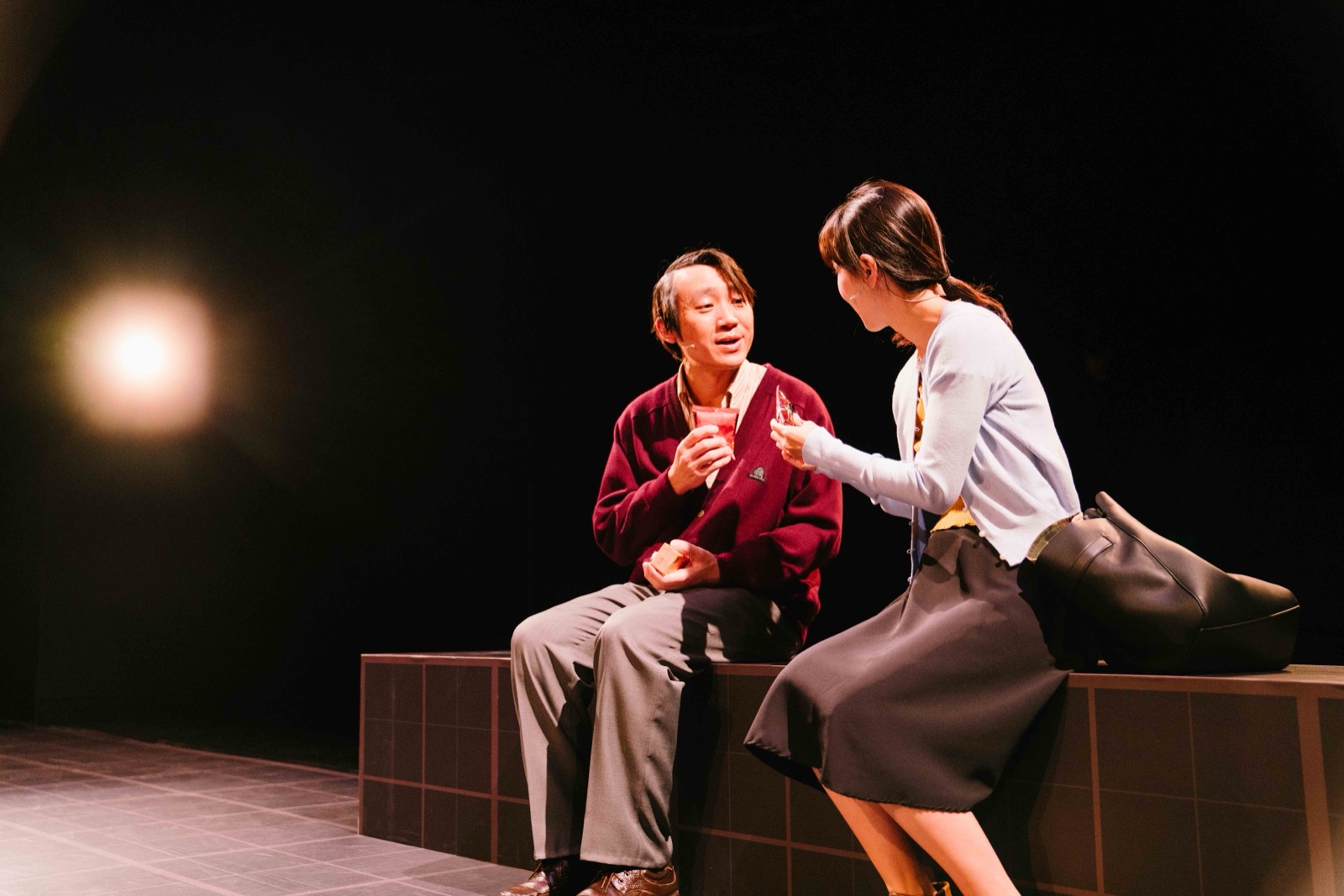 Couple sitting on stage edge in warm light