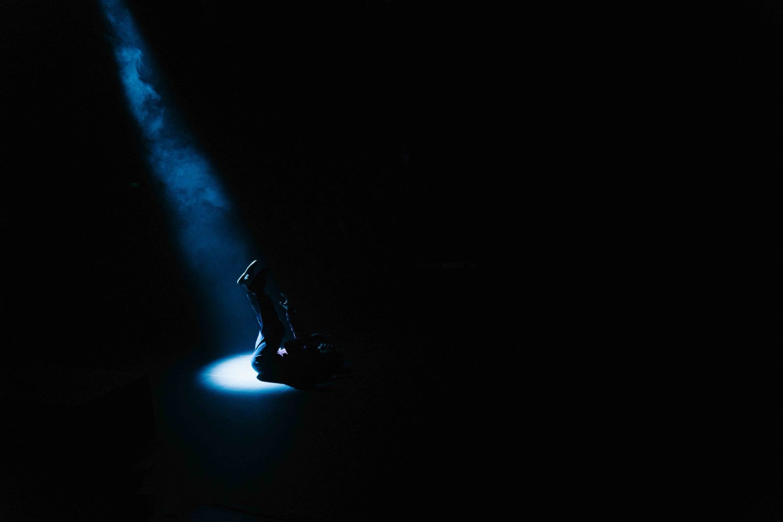 Figure crouched in blue beam