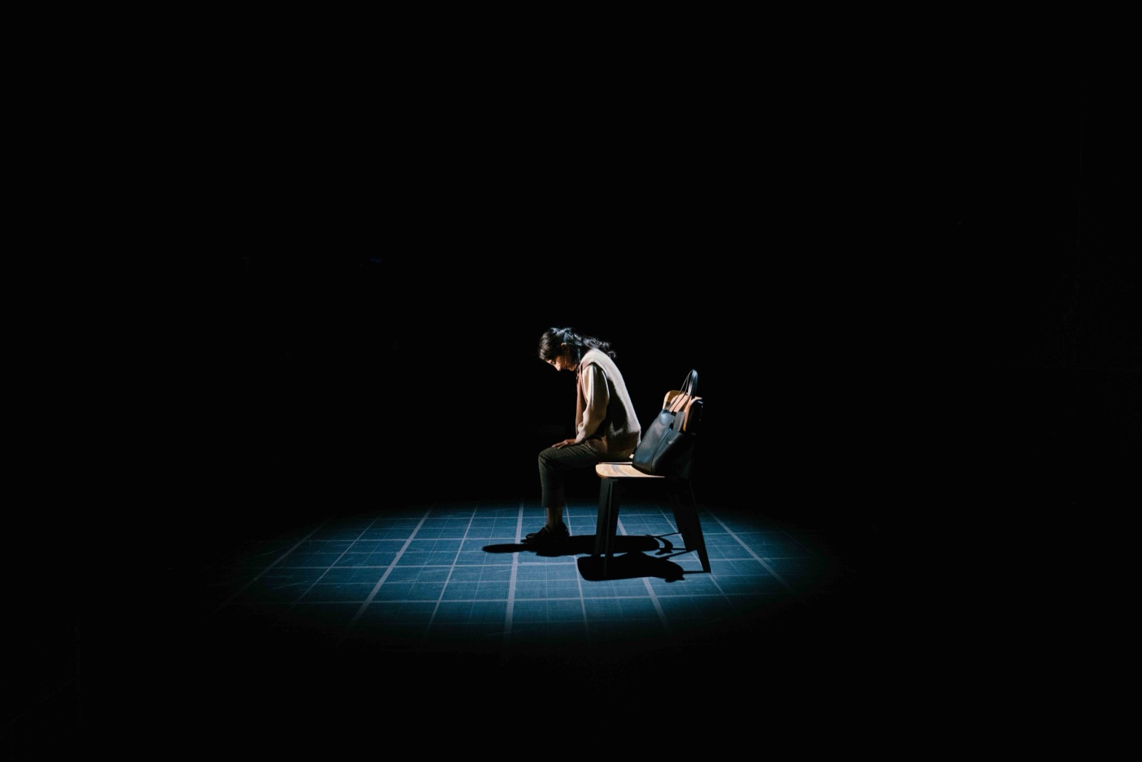 Woman alone on chair in blue spotlight