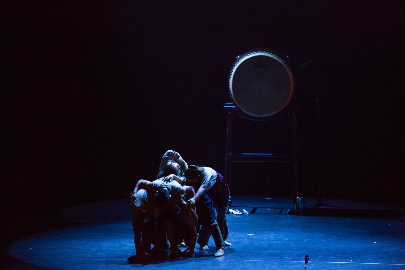 Dancers huddled in blue light with drum