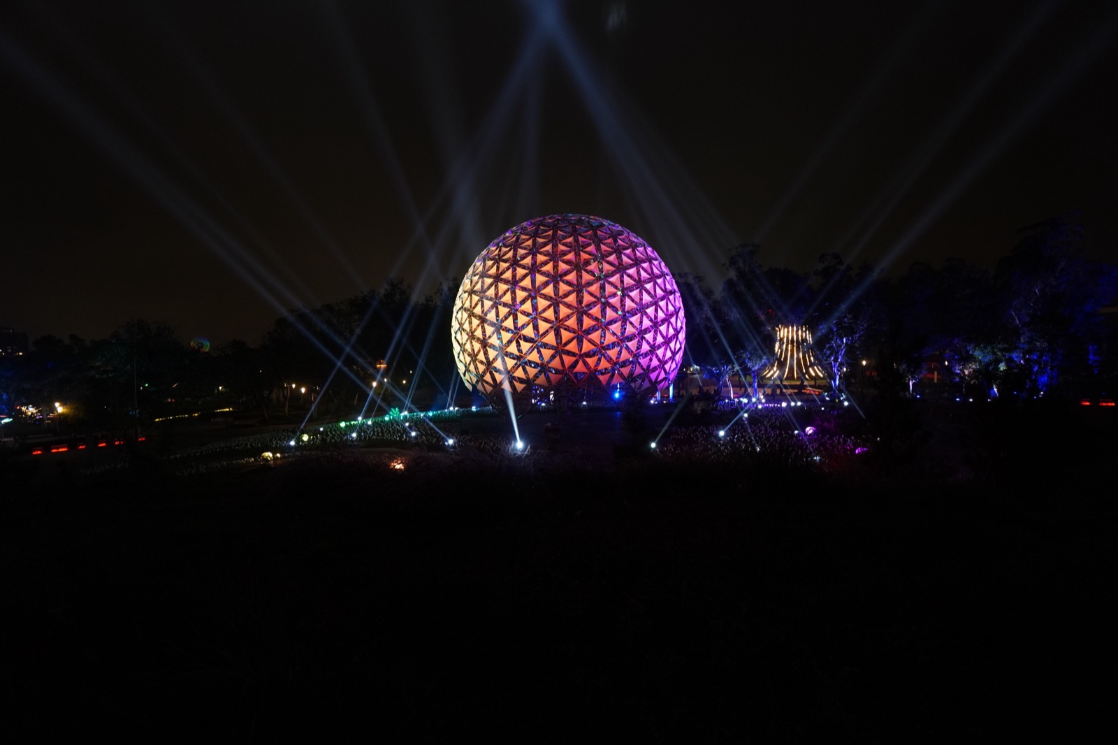 Sphere in orange-purple gradient with beams and illuminated pavilion